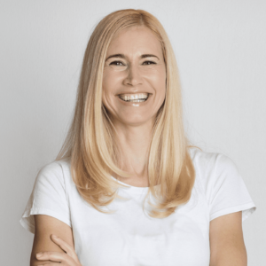 A woman with blonde hair wearing a white t-shirt, smiling