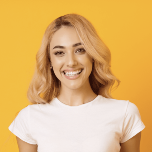 A woman wearing a white t-shirt smiles brightly, radiating joy and positivity.