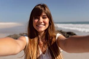 Beautiful young woman looking at camera on beach in the sunshine