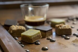 An closeup shot of different types of square-shaped sweets with tea on a wooden tray