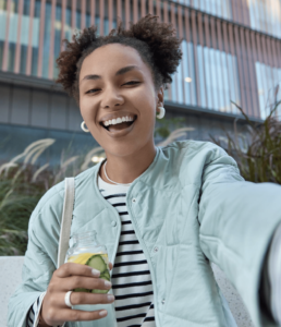 A smiling woman holding a drink, radiating joy and enjoying her moment.